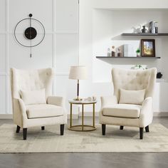 a living room with two chairs and a table in front of a clock on the wall