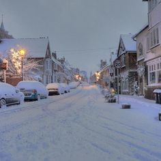 a snowy street lined with parked cars and buildings