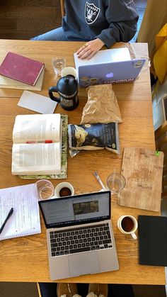 a laptop computer sitting on top of a wooden table next to a cup of coffee