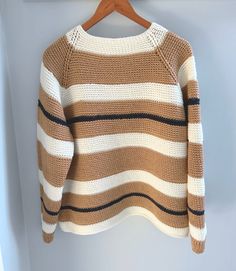 a brown and white striped sweater hanging on a wooden hanger