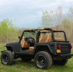 a black jeep with tan leather seats parked in the grass