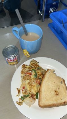 a white plate topped with a sandwich next to a cup of coffee and a can of tea