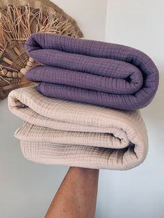 three blankets stacked on top of each other in front of a woven wall hanging basket