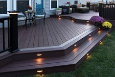 a deck with lights on it and some flowers in the grass