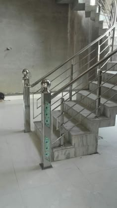 a set of stairs in an empty room with concrete walls and steel railings on either side