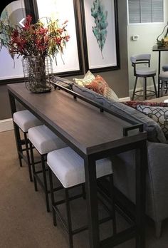 a living room filled with furniture next to a dining table and bar stools in front of a window