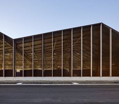 an empty parking lot in front of a large building with glass walls on each side