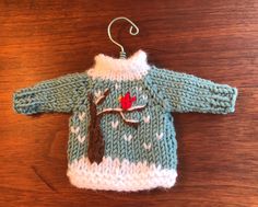 a knitted sweater with a bird on it is hanging from a wooden hanger