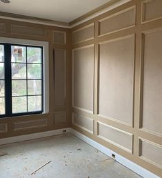 an empty room with wood paneling and a window in the corner that has no curtains