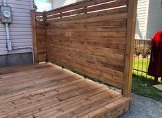 a wooden deck next to a house with a clock on the wall and fence around it