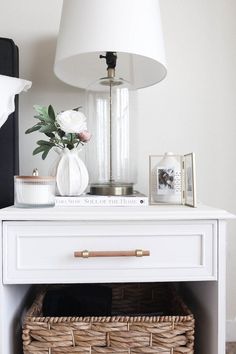 a white table topped with a lamp next to a wicker basket