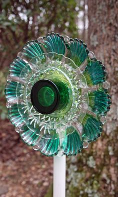 a green and white glass object sitting on top of a wooden pole