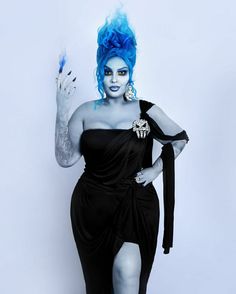 a woman with blue hair and makeup is posing for the camera while wearing a black dress