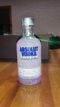 a bottle of absolut vodka sitting on a table with its light shining from behind it