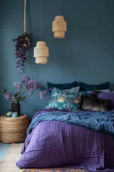 a bedroom with blue walls, purple bedding and flowers hanging from the ceiling above