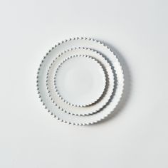 three white plates stacked on top of each other in the shape of a spiral, against a white background