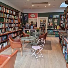 a library filled with lots of books next to tables and chairs on top of hard wood flooring