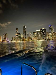 the city skyline is lit up at night as seen from a boat in the water