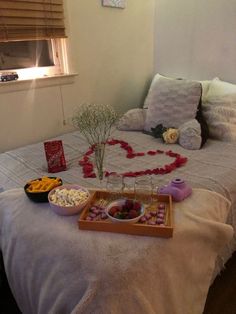 a bed topped with lots of food next to a vase filled with flowers and hearts