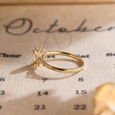 a gold ring sitting on top of a table next to a date sheet with the word october written in cursive writing