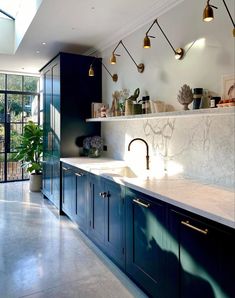 a kitchen with marble counter tops and blue cabinets, along with potted plants on the wall