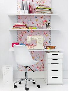 a white desk chair sitting in front of a shelf filled with books and sewing supplies