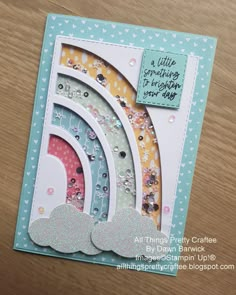 a card made with the rainbow and clouds stamp set on top of a wooden table