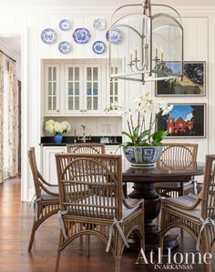 the dining room table is surrounded by wicker chairs and blue and white plates on the wall