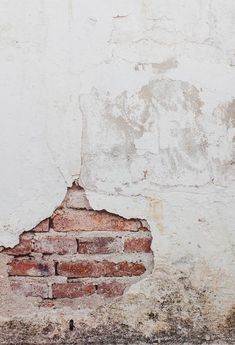 an old brick wall that has been painted white and is missing some paint on it