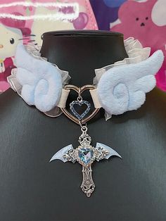 Elevate your Kawaii fashion game with our rhinestoned cross pendant blue/pink Jirai Kei angel wings PU choker. This stunning choker features a delicate PU leather band adorned with a rhinestoned cross pendant in a choice of blue or pink, perfectly capturing the ethereal essence of Jirai Kei style. The angel wings design adds a touch of whimsy and fantasy, making it a must-have accessory for any Kawaii wardrobe.  Please note that this product includes the choker only. Blue Aesthetic Accessories, Blue Accessories Aesthetic, Angelic Clothes, Angelic Accessories, Kawaii Wardrobe, Kawaii Choker, Harajuku Accessories, Wings Accessories, Collar Ideas