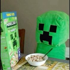 a bowl of cereal sitting on top of a table next to a green minecraft pillow