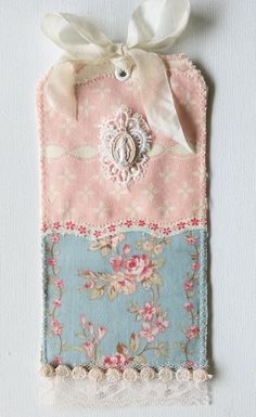 a pink and blue flowered bag with a white ribbon hanging from it's side