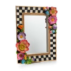 a mirror decorated with flowers and leaves on a checkerboard wallpapered frame