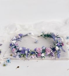 a white pillow with purple and blue flowers on top of it next to a flower crown