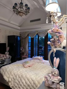 a room with a bed, chandelier and stuffed animals