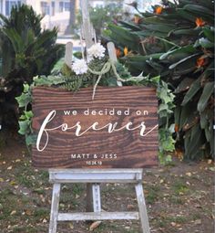 a wooden sign that says we decided on forever next to some flowers and greenery