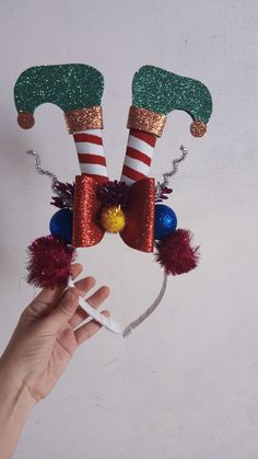 a hand holding up a christmas decoration made out of candy canes and santa hats