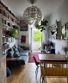 a living room filled with lots of furniture and bookshelves next to a window