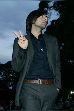 a man in a suit making the peace sign with his hand while standing outside at night