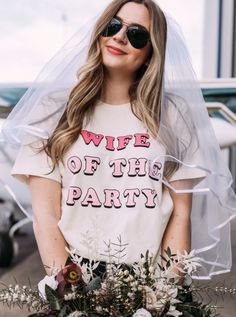 a woman wearing a t - shirt that says wife of the party with flowers in front of her