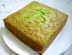 a square piece of cake on a white plate with green frosting in the middle