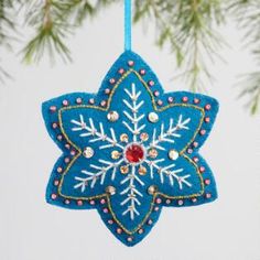 a blue ornament hanging from a christmas tree with snowflakes on it