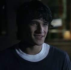 a smiling young man in a dark room