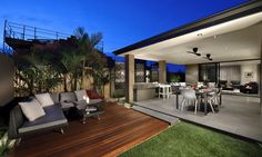 an outdoor living room and dining area are lit up at night