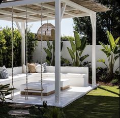 a white couch sitting on top of a lush green field next to a covered patio