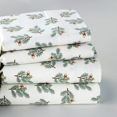 four folded sheet sets with holly and star designs on white fabric, sitting next to each other