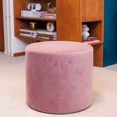 a pink stool sitting in front of a book shelf