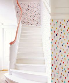 a white staircase with colorful polka dots on the wall next to it and a pink handrail