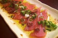 a white plate topped with meat and veggies on top of a wooden table