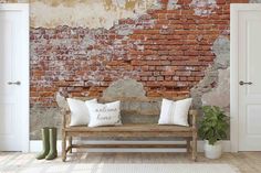 an old brick wall with two white pillows on a wooden bench in front of it